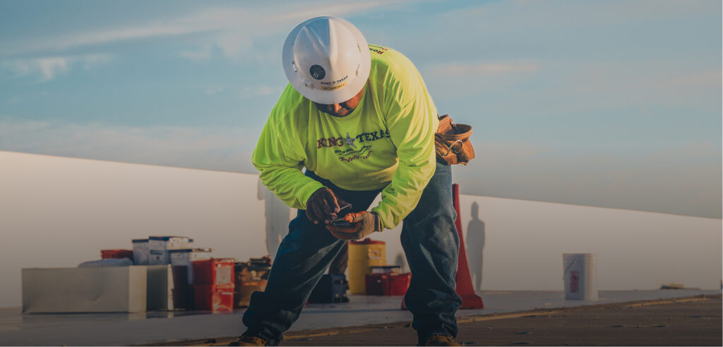 King of Texas roofer fastening membrane seams during commercial roof installation.