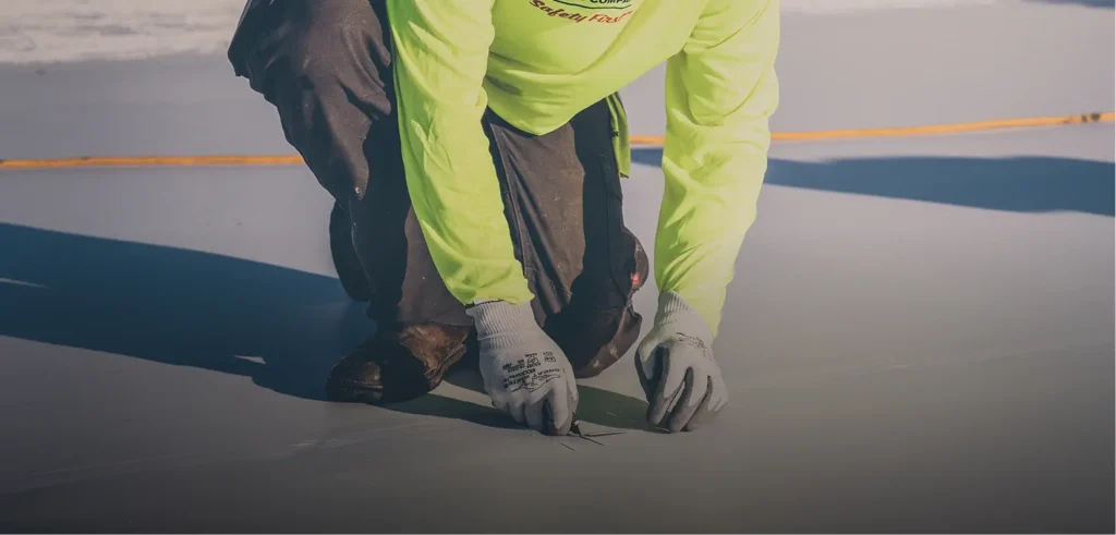 Close-up of King of Texas technician detailing roof membrane seams for precision repair.