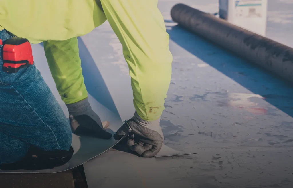 King of Texas roofer securing roofing material at roof edge during maintenance work.